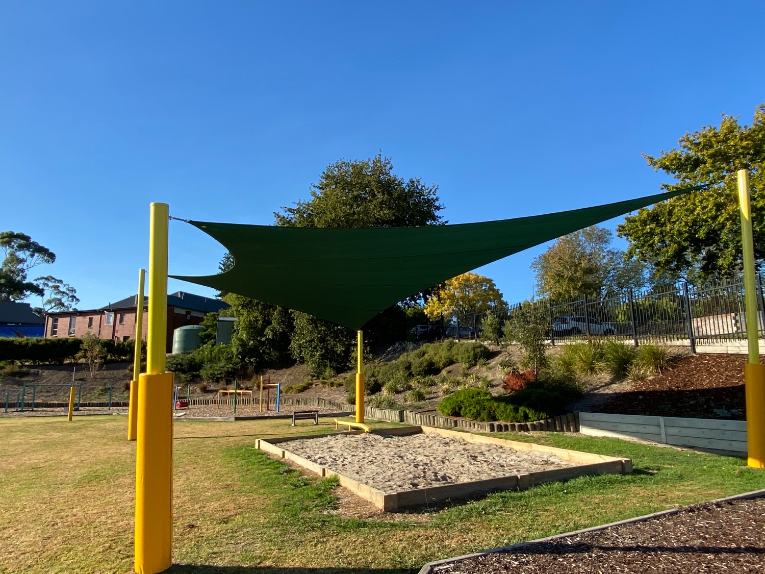 School Shade Sails over a sand pit - Yellow posts and Green Shade Mesh Sail