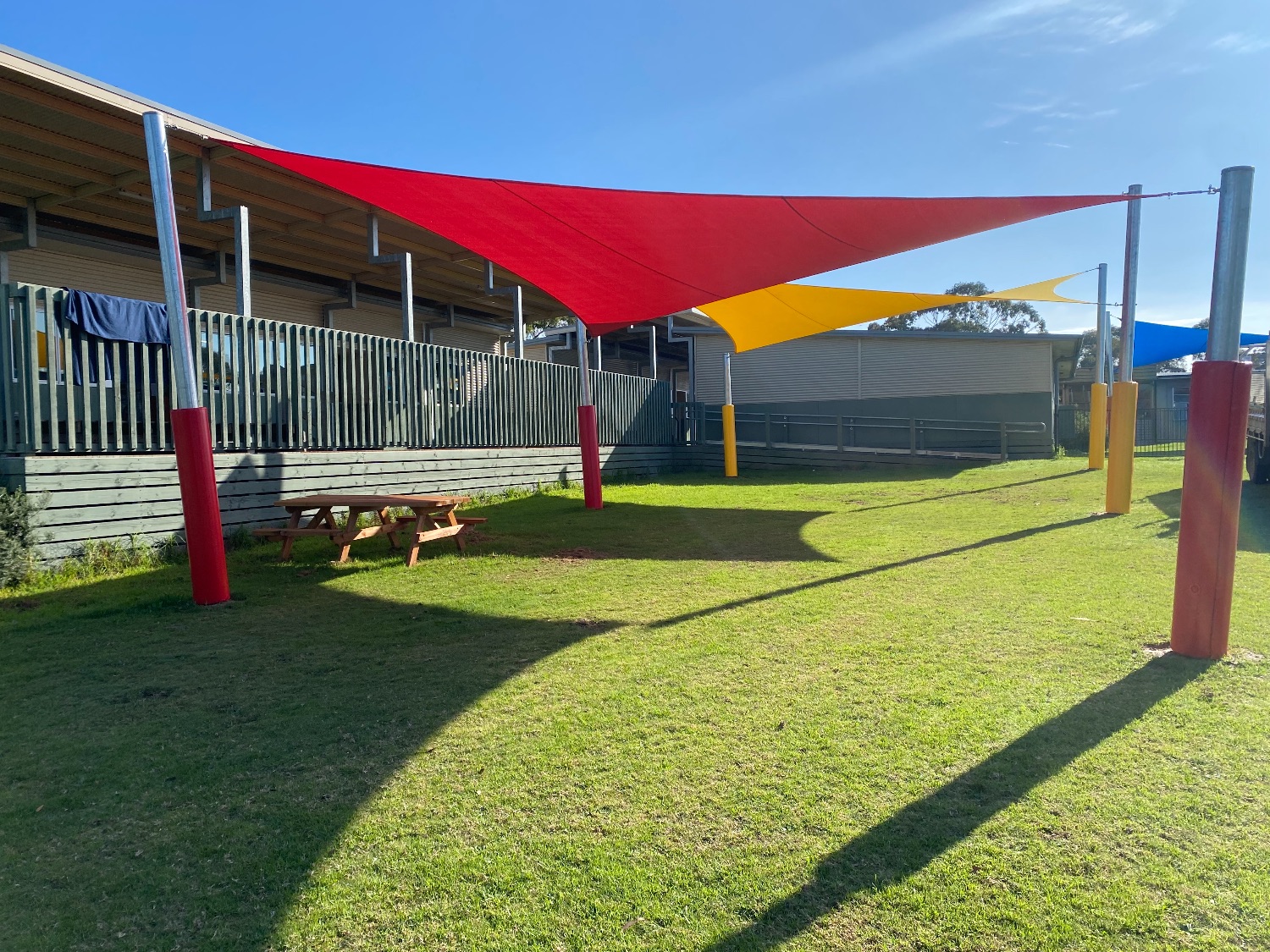 Red and Yellow Primary School Shade Sails over a grass play area