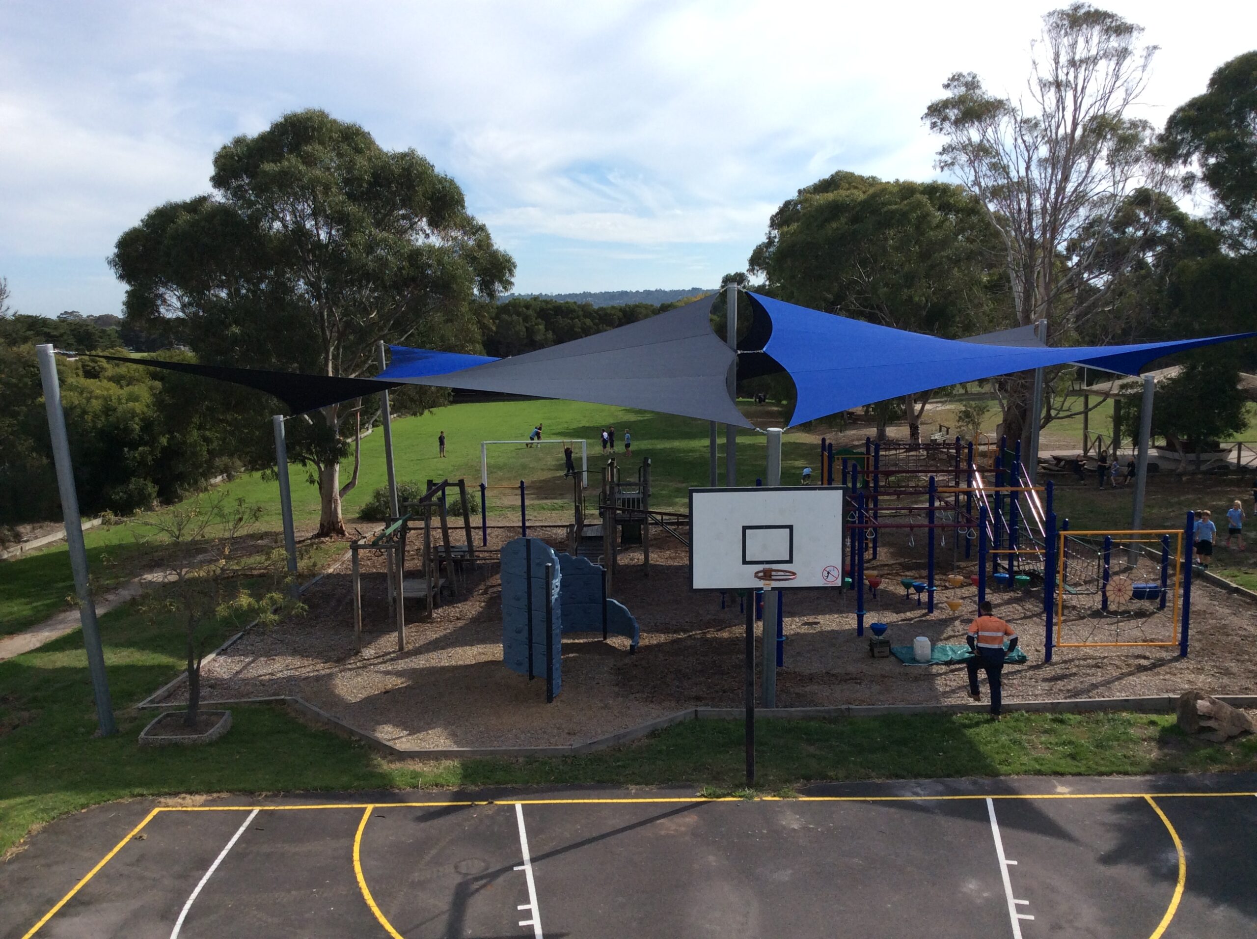 School Shade Sails over a playground. Sails are next to a basketball court